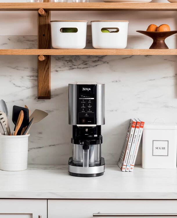 A coffee maker sits on a counter beneath a shelf, showcasing a functional kitchen setup.