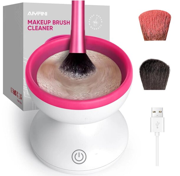 A pink brush rests beside a white cup containing another brush, set against a neutral background.