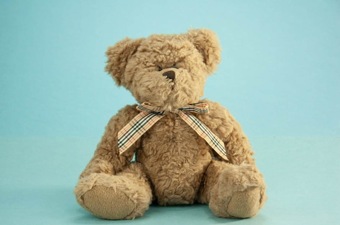 A teddy bear sitting against a solid blue background, showcasing its soft fur and friendly expression.