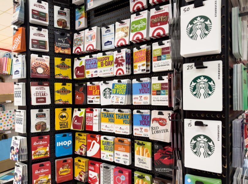 Multiple Starbucks gift cards showcased on a display rack in a retail environment.