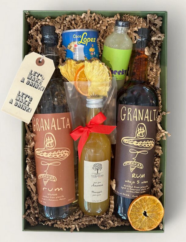 A gift box containing a bottle of rum, orange juice, and a bottle of wine, arranged attractively.