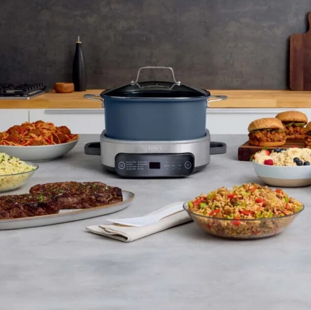 A kitchen counter featuring a crock pot, bowls of food, and a fresh salad, creating a cozy meal preparation scene.