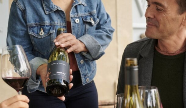 A man and woman clink wine glasses together, smiling in a celebratory moment.