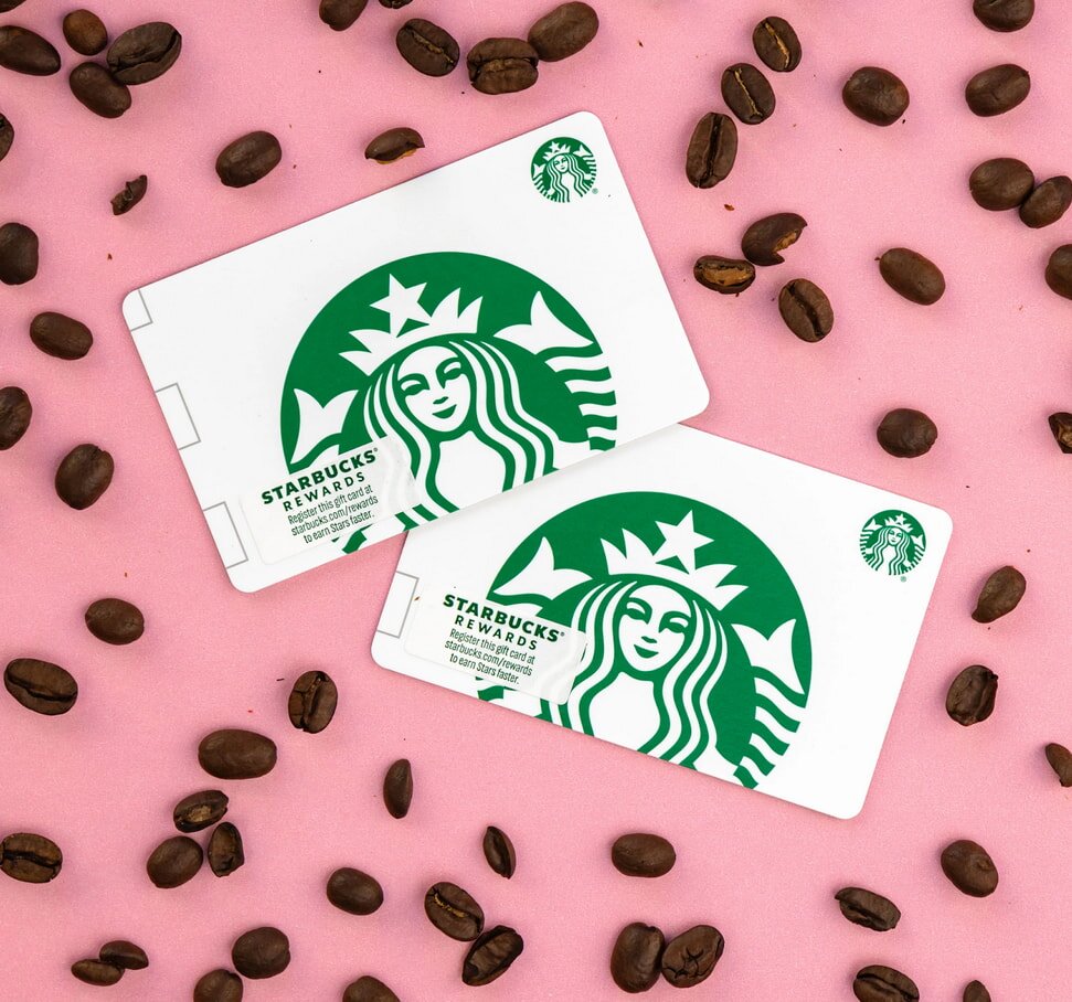 Starbucks gift cards are arranged among scattered coffee beans, creating a warm, inviting coffee-themed display.