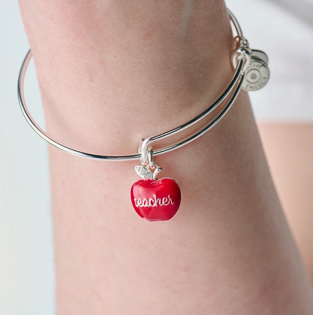 A woman showcases a charm bracelet featuring red apple charms, highlighting her unique and playful style.