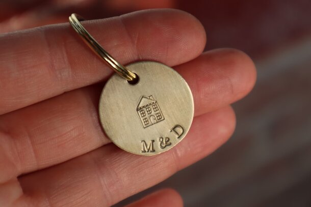 A person holds a keychain featuring a small house, symbolizing home ownership or a new beginning.