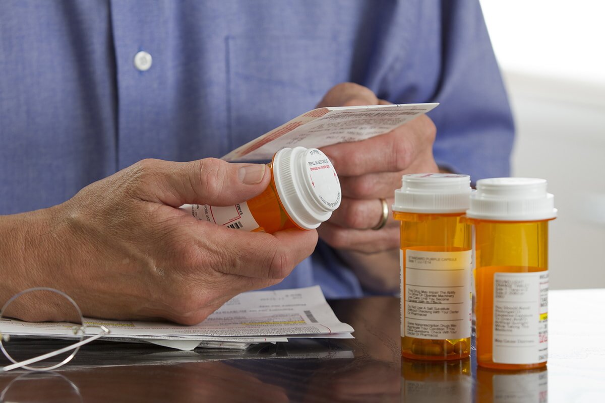 Man reading prescription label on orange pill bottle