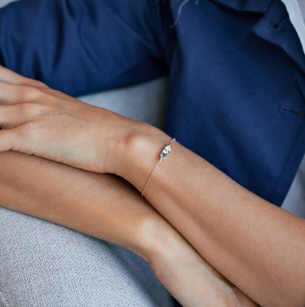 A woman showcases a bracelet featuring a prominent blue diamond on her wrist.
