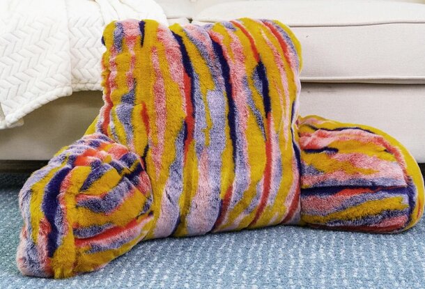 A colorful striped pillow resting on the floor, featuring vibrant hues and a soft texture.