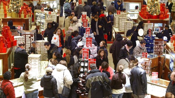 A busy mall filled with shoppers browsing various stores and interacting in a lively atmosphere.