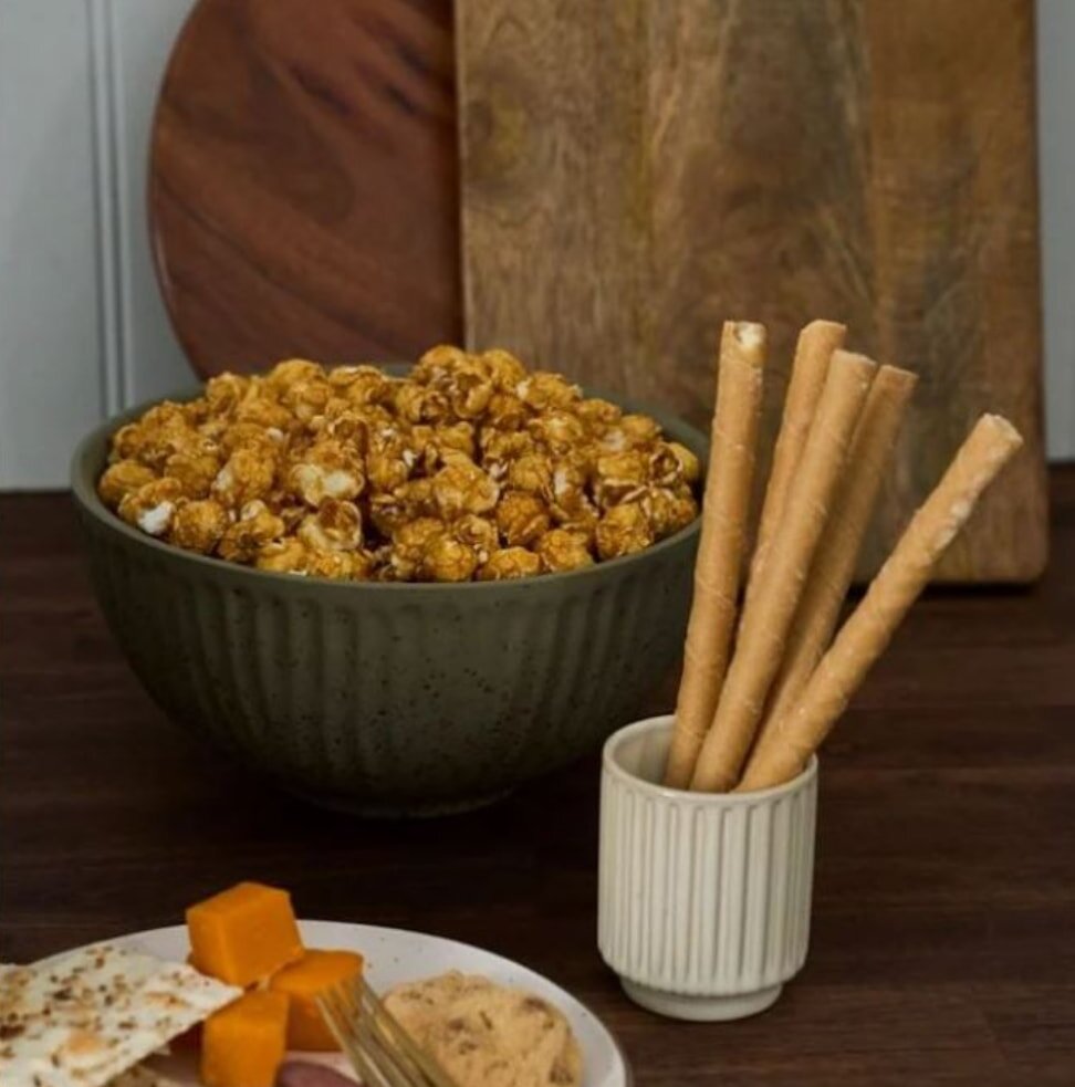 A cozy movie night snack spread, featuring popcorn, candy, and drinks on a table in a dimly lit living room.