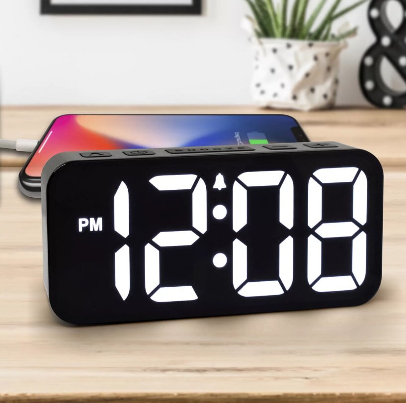 Black digital alarm clock on wooden desk