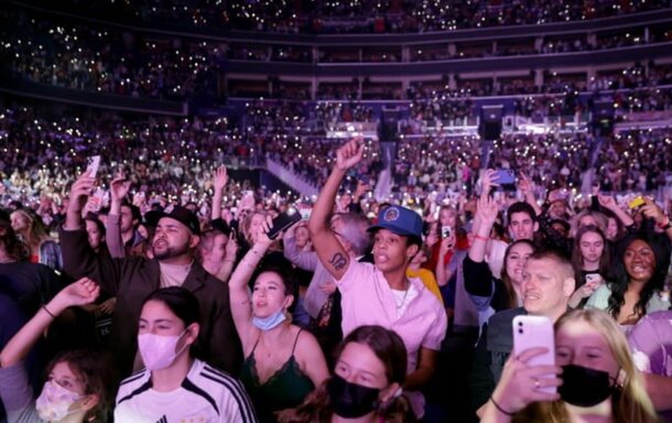 A lively crowd at a concert, with many people raising their hands in excitement and enjoyment.