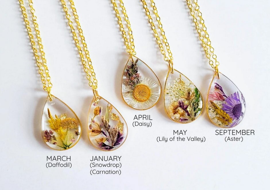 A collection of four dried flower types is artistically arranged on gold chains, highlighting their delicate textures and hues.