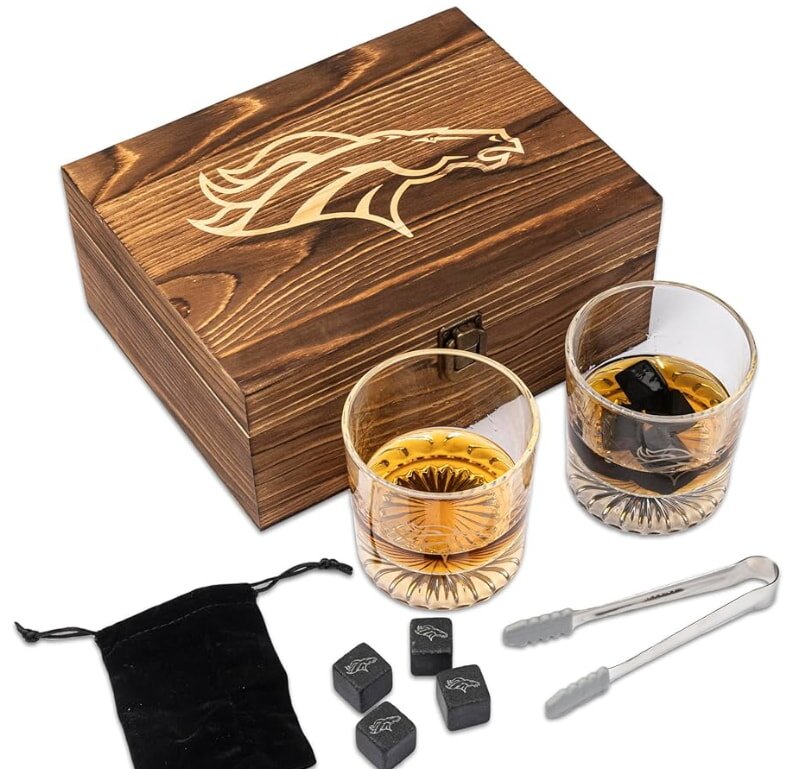 Wooden gift box featuring a horse design, two whiskey glasses with dark cooling stones, metal tongs, and a black pouch, conveying elegance and sophistication.