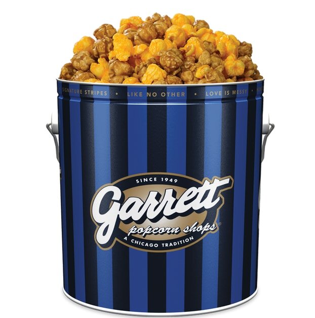 A blue-striped Garrett popcorn tin filled with caramel and cheese popcorn, showcasing the Chicago tradition since 1949.