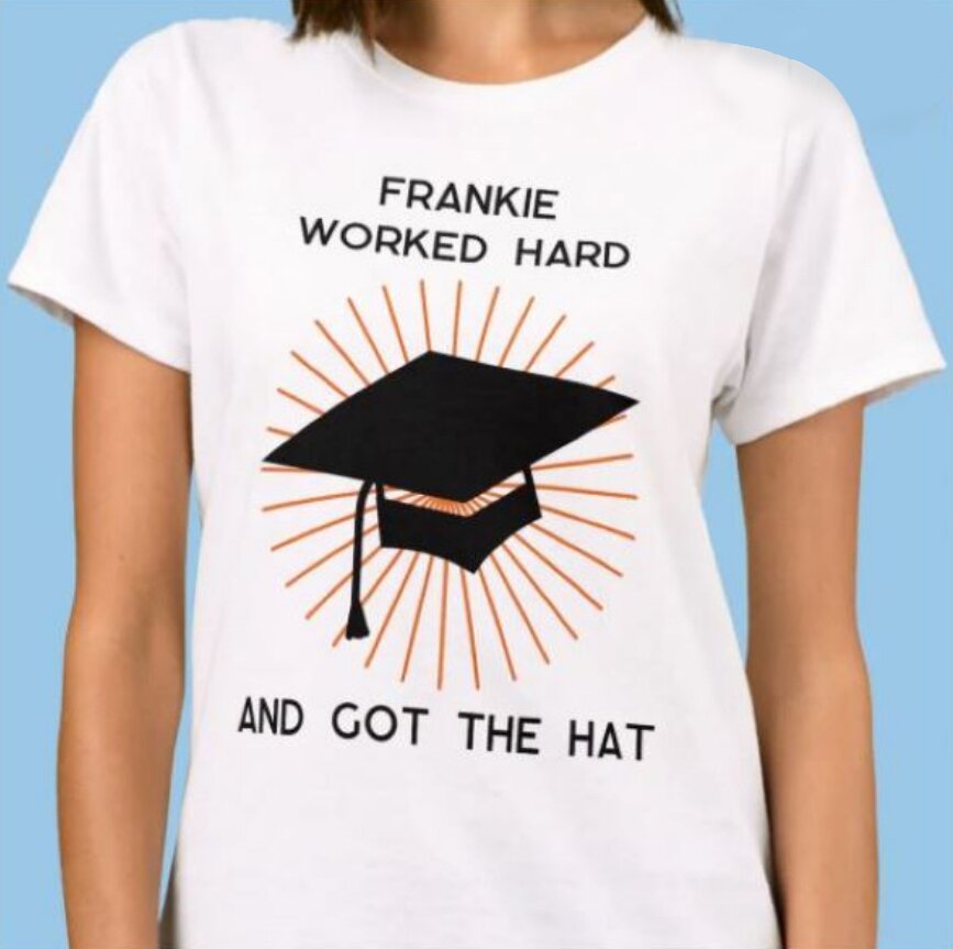 A woman in a white t-shirt reads "Frankie worked hard and got the hat," smiling at the camera.