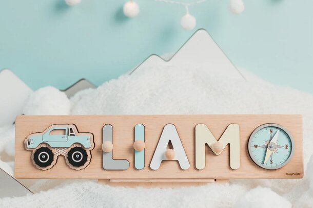 A wooden clock beside a nameplate featuring a truck and snow, showcasing a winter-themed design.