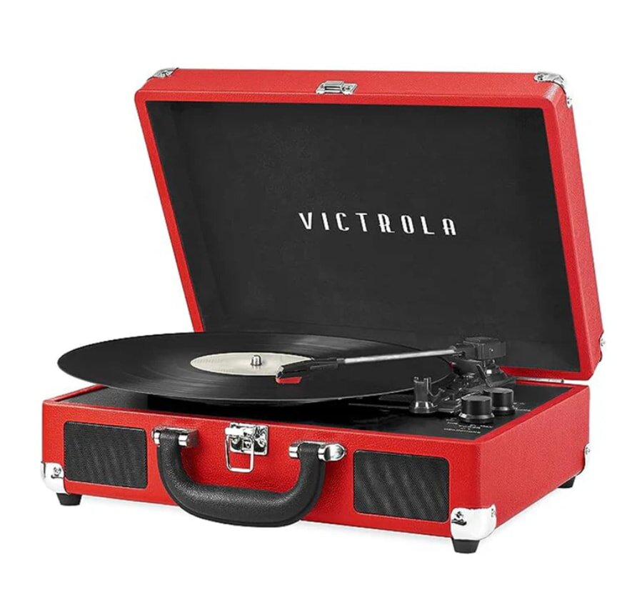 Red portable record player with "Victrola" on the open lid. It has a vinyl record spinning, and features a black handle and silver clasps, conveying a retro vibe.