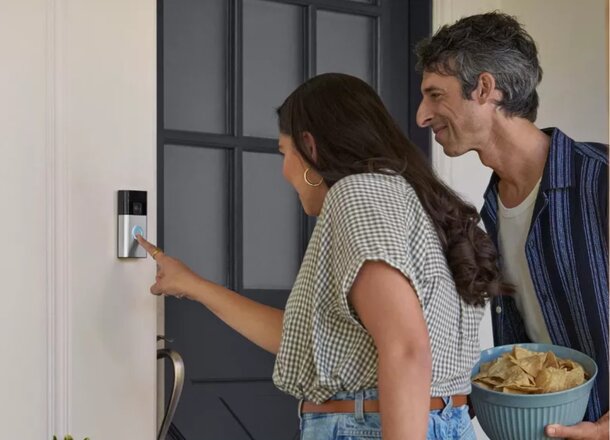 A man and woman are opening the front door to a house together, smiling as they enter.