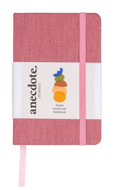 A pink notebook featuring a label on its cover, resting on a flat surface.
