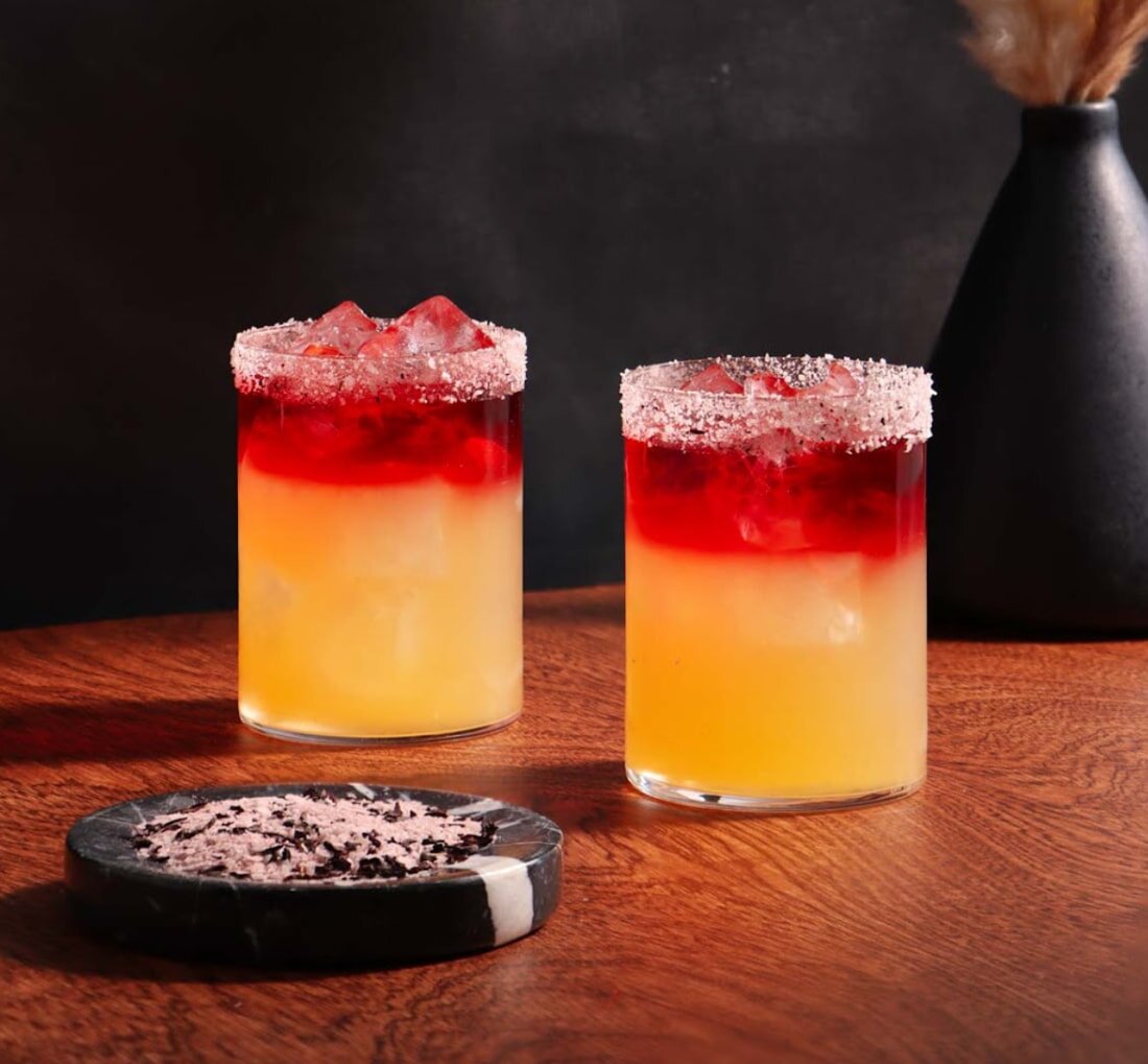 Two cocktails adorned with vibrant red and yellow garnishes, showcasing a refreshing and colorful presentation.