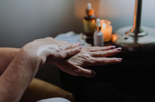 A woman's hands are coated in a thick cream, showcasing a moisturizing treatment or skincare application.