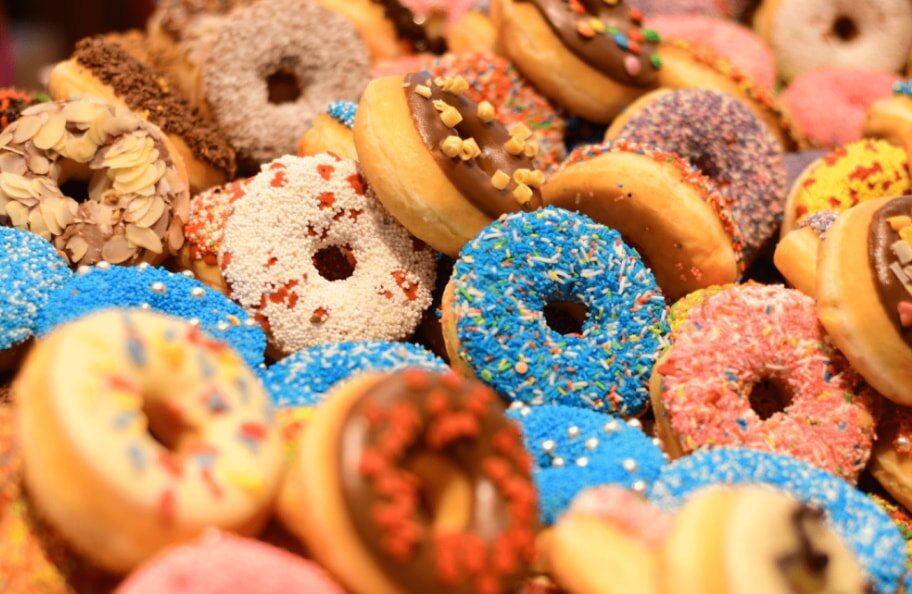 A colorful assortment of donuts with various toppings, including sprinkles, nuts, and chocolate glaze, creating a vibrant and indulgent display.