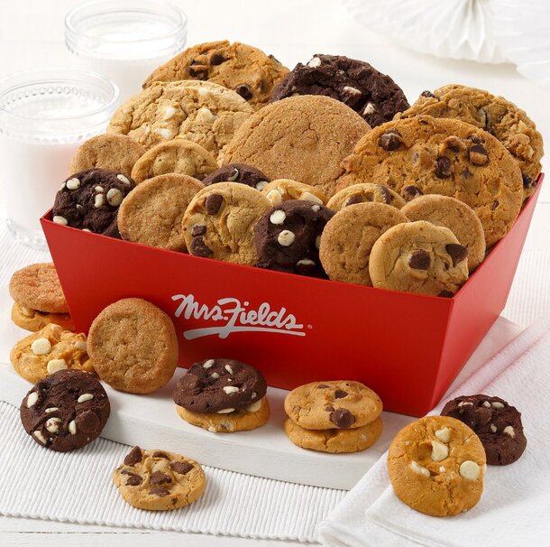 A red box filled with assorted cookies and a glass of milk placed beside it.