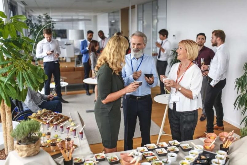 A group of people gathered around a table filled with various food and drinks, engaging in conversation and enjoying the moment.