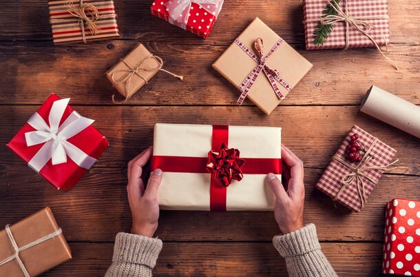 A woman's hands hold a red and white wrapped gift, showcasing the festive design and her delicate grip.
