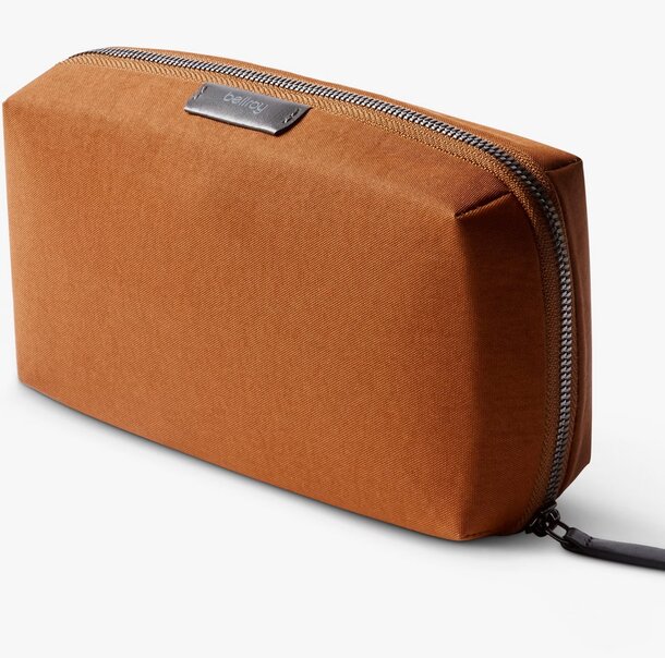 Small brown fabric toiletry bag displayed on a neutral background.