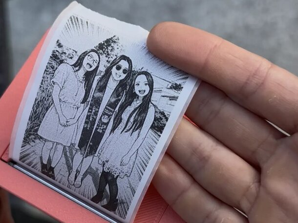 A person holds a photo featuring three smiling girls outdoors, showcasing a moment of friendship and joy.