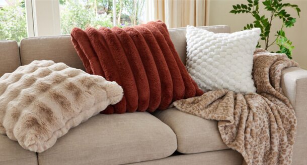 A cozy couch adorned with colorful pillows and soft blankets, inviting relaxation and comfort.