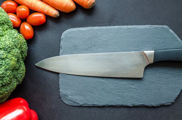 A knife rests on a cutting board surrounded by various chopped vegetables.