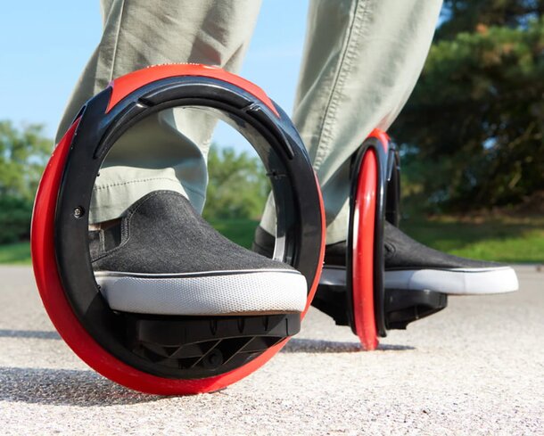 A person in sneakers stands beside a red and black wheel, showcasing a casual and sporty vibe.