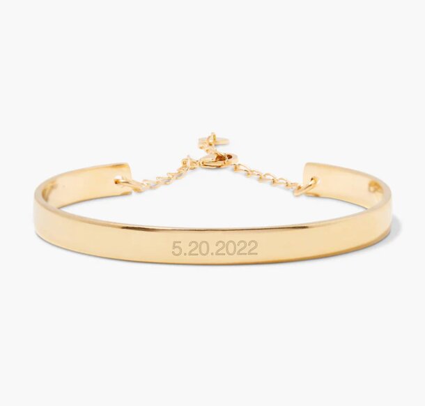 A gold bracelet featuring an engraved date, showcasing a simple yet elegant design.