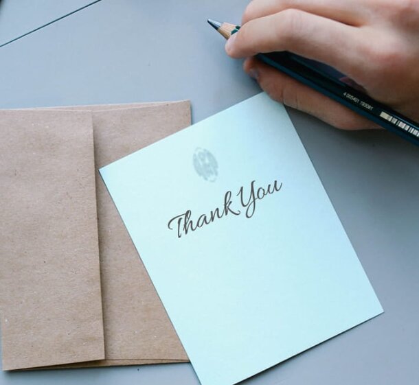 Thank you card with a decorative design and a pen resting beside it on a wooden surface.