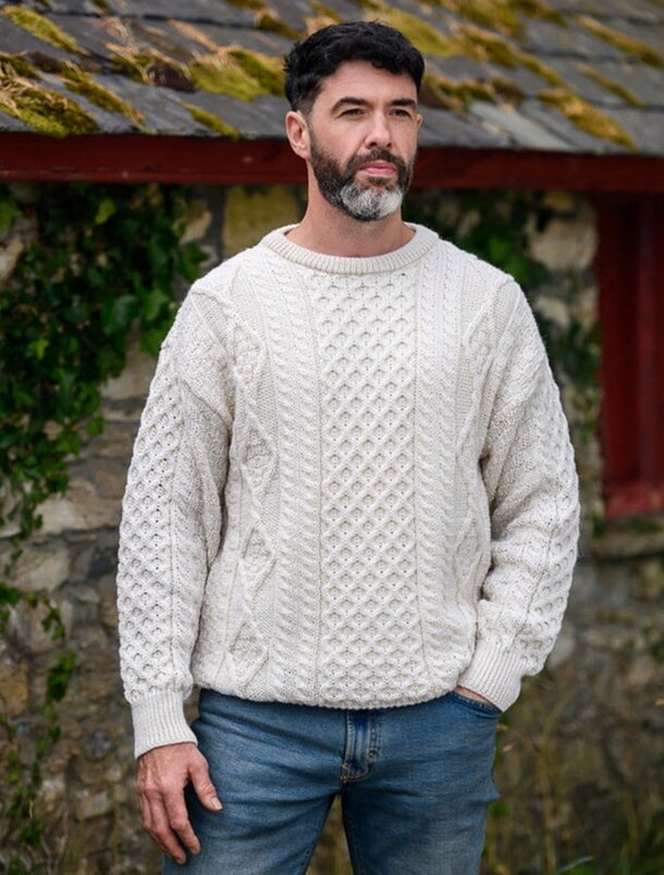 A man in a white sweater stands in front of a bright red building, showcasing a vibrant urban scene.  