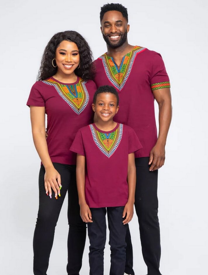 A family poses together, all wearing vibrant African print shirts, showcasing colorful patterns and cultural pride.