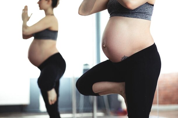 Two pregnant women practicing yoga poses in a serene setting, promoting wellness and mindfulness during pregnancy.