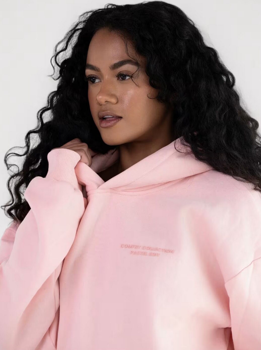 A pink women's hoodie featuring the phrase "love yourself" prominently displayed on the front.