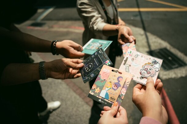 A group of people facing each other, each holding cards in their hands, engaged in a game or activity.