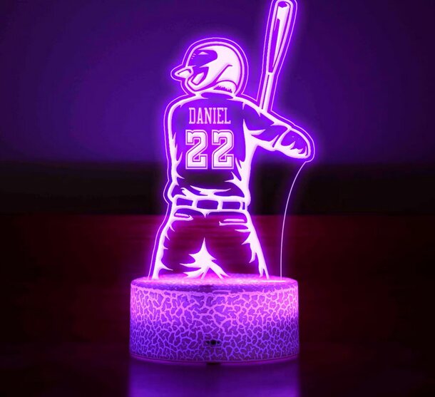 A purple night light featuring a baseball player design, illuminating a cozy space with a playful sports theme.