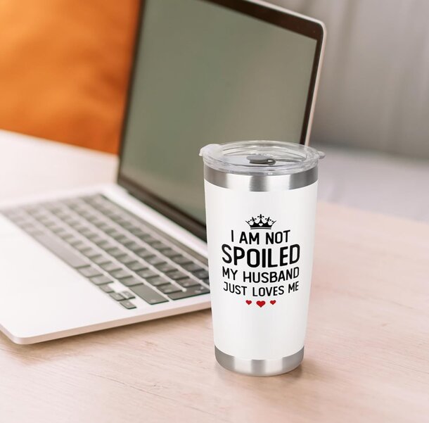 Text on a humorous sign reads, "I am not spoiled, my husband is," highlighting a playful relationship dynamic.