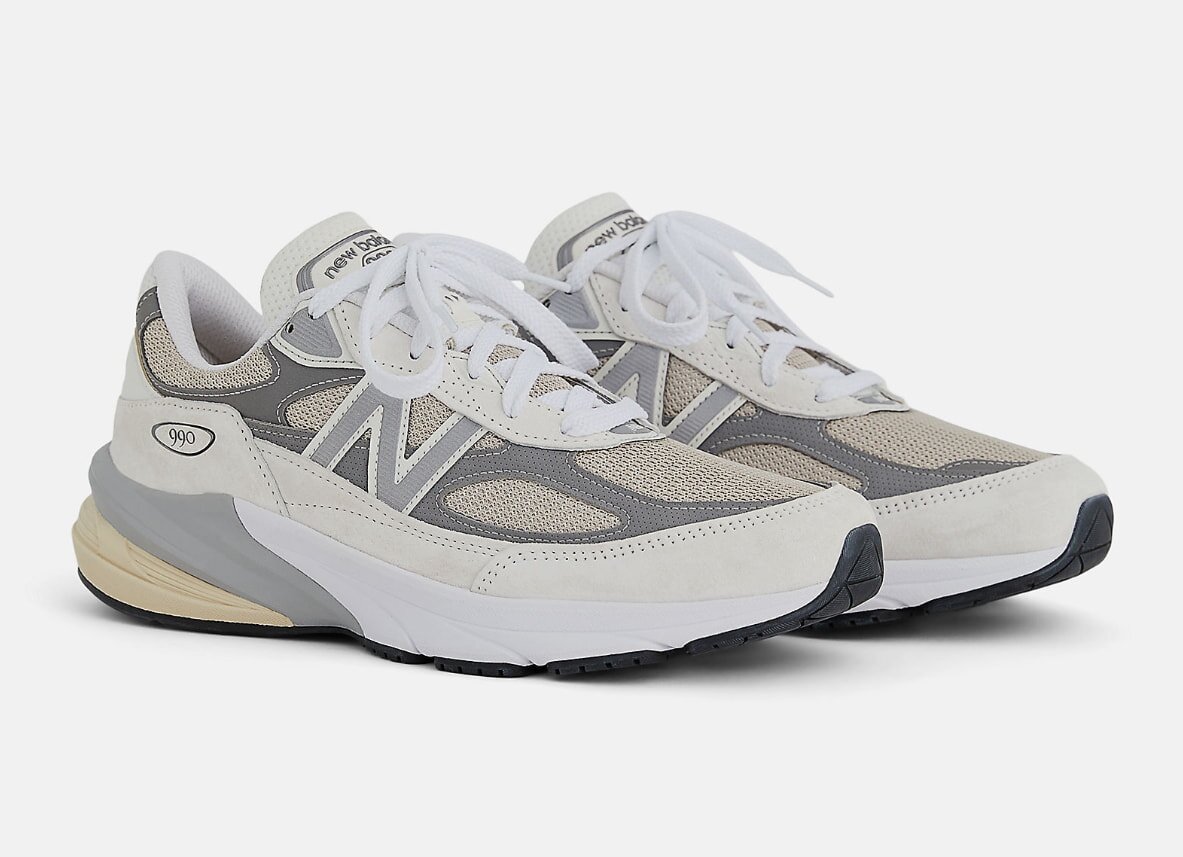 New Balance 990 sneakers in a white and beige color scheme, showcasing a classic athletic design.