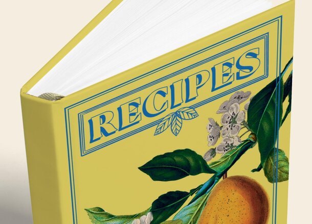 A book resting on a surface, adorned with an orange and green leaves beside it.