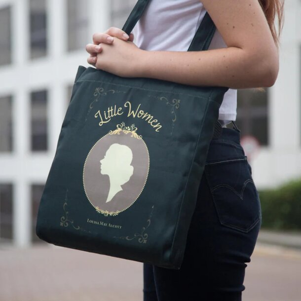 A woman holds a green tote bag featuring an illustration of another woman on its surface.