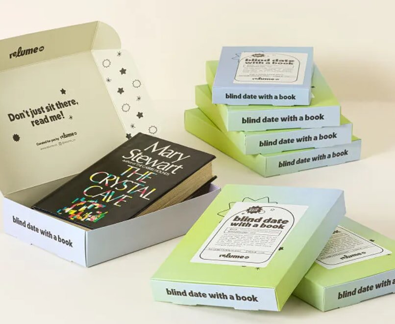 A collection of books in a box, featuring one book visible at the top of the stack.