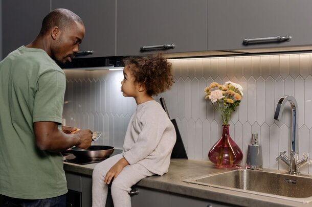A man and a young girl are together in a kitchen, engaged in a cooking activity.